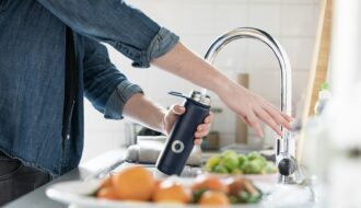 person in blue denim jacket holding stainless steel bottle