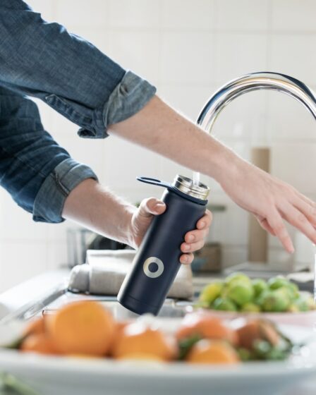 person in blue denim jacket holding stainless steel bottle