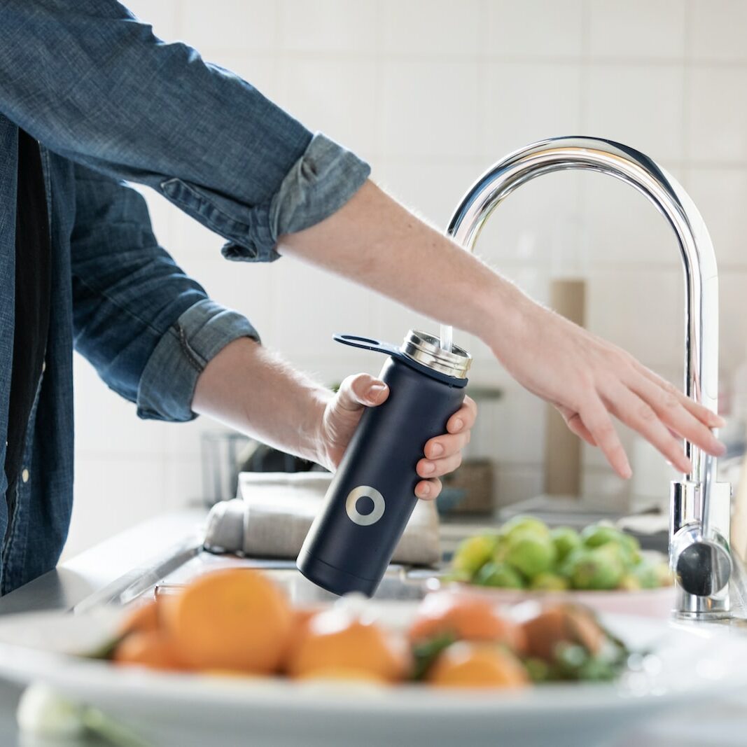 person in blue denim jacket holding stainless steel bottle